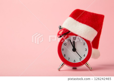 Red alarm clock with Christmas Santa hat on pink background. Top view. 126242465