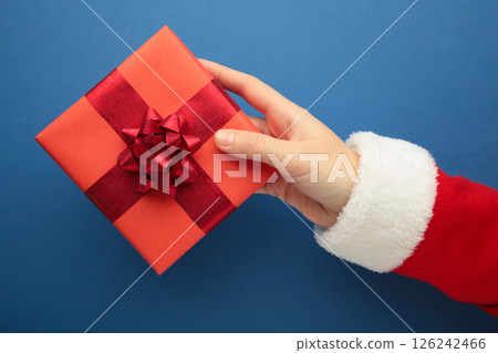 Merry Christmas concept, Top view of Santa claus hands is holding a red gift box on blue background. 126242466