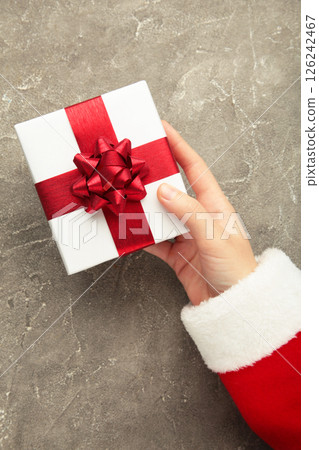 Merry Christmas concept, Top view of Santa claus hands is holding a white gift box on grey background. Vertical photo 126242467