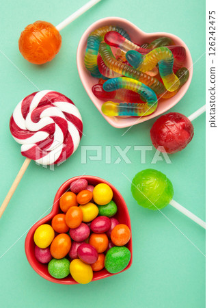 Different types of candies on purple background, copy space. Colorful birthday party background. Vertical photo 126242475