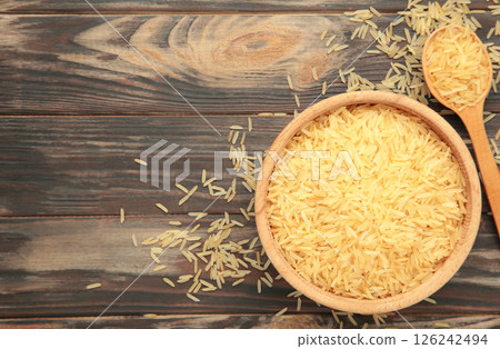 Rice grains on brown plate and spoon on brown wooden background 126242494
