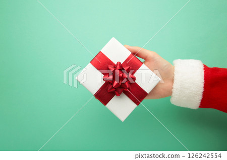 Merry Christmas concept, Top view of Santa claus hands is holding a white gift box on mint background. 126242554