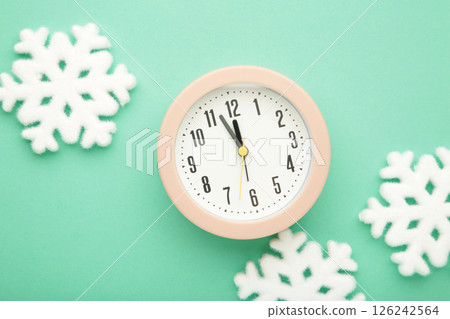 Alarm clock with white snowflakes on mint background. Alarm clock with white snowflakes on mint background. 126242564