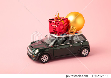 Green toy car with gift on pink background. Concept of celebrating Christmas and New Year. Top view 126242565