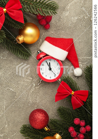 Alarm clock with Santa hat white fir tree on grey background. Vertical photo Alarm clock with Santa hat white fir tree on grey background. Vertical photo 126242566
