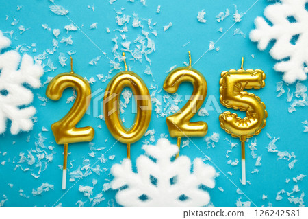 Holiday background Happy New Year 2025. Numbers of year 2025 made by gold candles with snowflakes on blue background. Holiday background Happy New Year 2025. Numbers of year 2025 made by gold candles with snowflakes on blue background. 126242581
