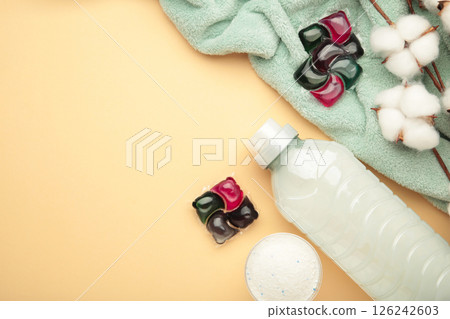 Gel capsules with laundry detergent and soft fabric texture on beige background. Top view 126242603
