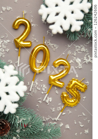 Holiday background Happy New Year 2025. Numbers of year 2025 made by gold candles with snowflakes on grey background. Vertical photo Holiday background Happy New Year 2025. Numbers of year 2025 made by gold candles with snowflakes on grey background. Vertical photo 126242606