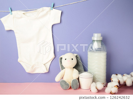 Laundry detergent products with white baby cloth and cotton flower on purple background. Top view Laundry detergent products with white baby cloth and cotton flower on purple background. Top view 126242632