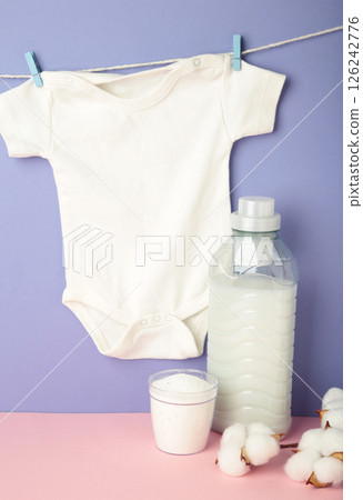 Laundry detergent products with white baby cloth and cotton flower on purple background. Top view Laundry detergent products with white baby cloth and cotton flower on purple background. Top view 126242776