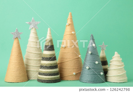 Handmade Christmas trees on mint background. Yarn wrapped cone trees. DIY concept 126242798