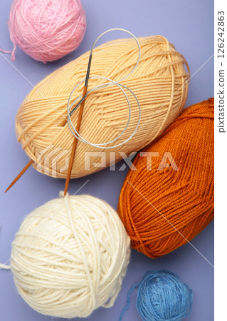 Different yarns, knitting needles on violet background. Autumn. Vertical photo Different yarns, knitting needles on violet background. Autumn. Vertical photo 126242863