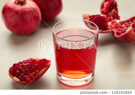 Natural, fresh pomegranate juice in a glass with pomegranates on light background. Top view Natural, fresh pomegranate juice in a glass with pomegranates on light background. Top view 126242884