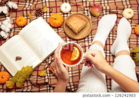 Autumn background with woman legs with tea, pumpkins and book. top view 126242983