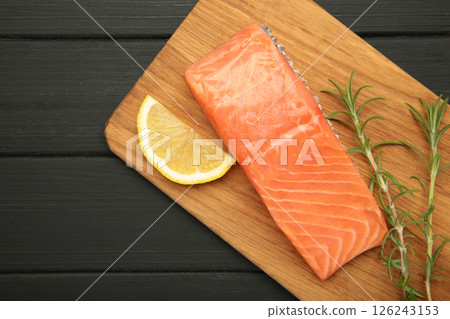 Red fish. Raw salmon fillet with rosemary and lemon on cutting board on black wooden background. Red fish. Raw salmon fillet with rosemary and lemon on cutting board on black wooden background. 126243153