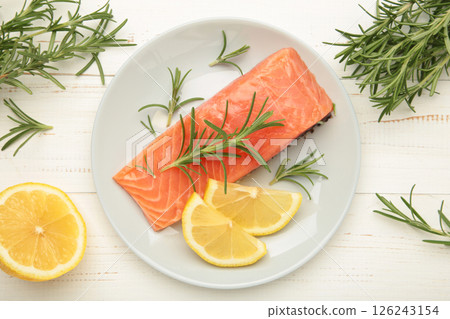 Red fish. Raw salmon fillet with rosemary and lemon on grey plate on white background. Red fish. Raw salmon fillet with rosemary and lemon on grey plate on white background. 126243154