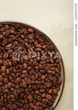Coffee beans on wooden plate on light background. Vertical photo 126243158