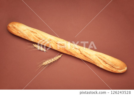 Fresh baguette bread on a brown background. 126243528