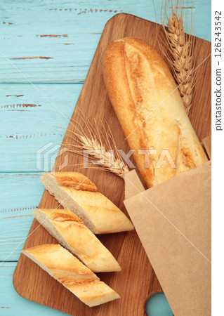 Baguette whole and cut into pieces on cutting board on blue wooden background 126243542