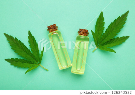 Glass bottles with CBD oil, thc tincture, hemp leaves on mint background. Cosmetics CBD hemp oil Glass bottles with CBD oil, thc tincture, hemp leaves on mint background. Cosmetics CBD hemp oil 126243582