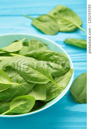 Baby spinach leaves with water drops in mint bowl on blue wooden background. Raw organic spinach greens. Vertical photo 126243595