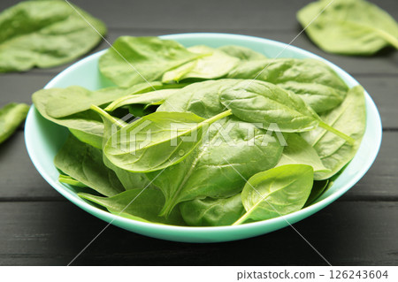 Baby spinach leaves with water drops in mint bowl on black wooden background. Raw organic spinach greens 126243604
