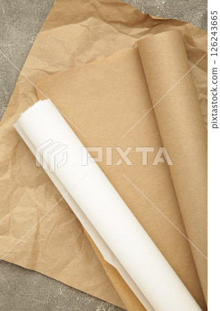 Rolls of white and brown baking paper on grey concrete background. Vertical photo 126243665
