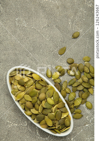 Pumpkin seeds in white plate on grey concrete background. 126243667