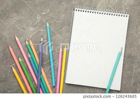 Open notebook with colorful pencil on grey concrete background. 126243685