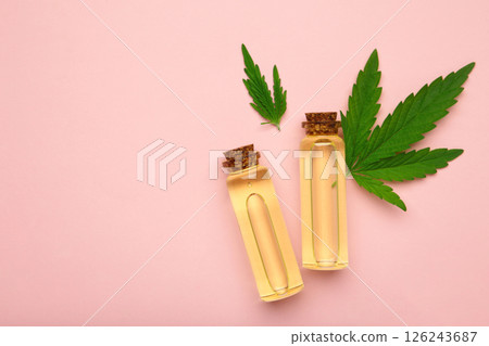 Glass bottles with CBD oil, thc tincture, hemp leaves on pink background. Cosmetics CBD hemp oil. Space for text 126243687