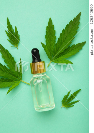 Little bottle with hemp oil and leaf on mint background. Vertical photo 126243690