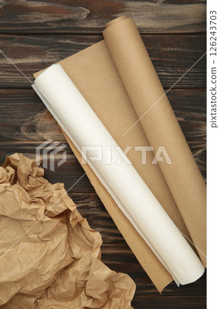 Rolls of white and brown baking paper on brown wooden background. Vertical photo 126243703
