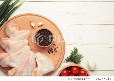 Raw chicken wings with ingredients for cooking on wooden cutting board on white wooden background Raw chicken wings with ingredients for cooking on wooden cutting board on white wooden background 126243715
