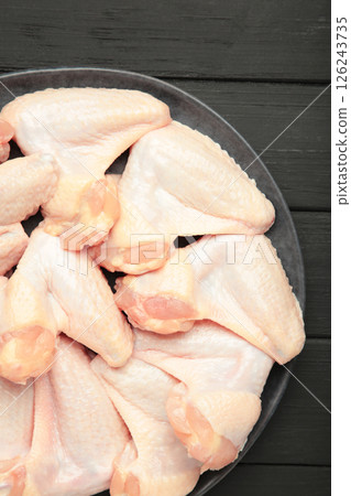 Raw chicken wings on dark plate on black wooden background. Vertical photo Raw chicken wings on dark plate on black wooden background. Vertical photo 126243735