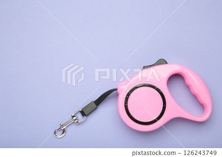Pink plastic durable and ergonomic leash roulette for pets on purple background. Convenient mechanical device for keeping and controlling dog in street. Pink plastic durable and ergonomic leash roulette for pets on purple background. Convenient mechanical device for keeping and controlling dog in street. 126243749
