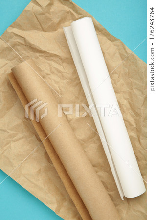 Rolls of white and brown baking paper on blue background. Vertical photo Rolls of white and brown baking paper on blue background. Vertical photo 126243764