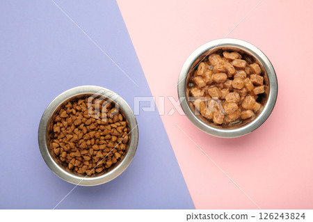 Wet and dry food for dogs and cats in silver bowl on pink background. Wet and dry food for dogs and cats in silver bowl on pink background. 126243824