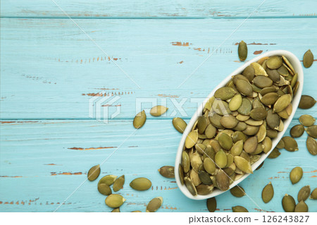 Pumpkin seeds in white bowl on blue wooden background, top view 126243827