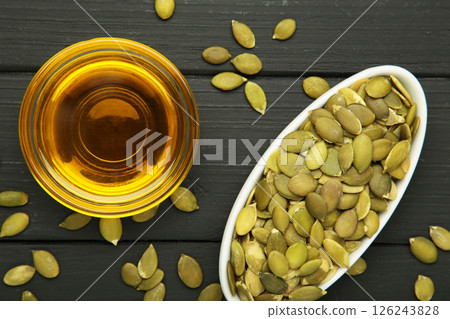 Pumpkin seed oil and seeds on black wooden background. 126243828