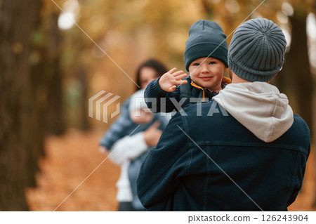 Boy is on the dad's hands. Father with his son on hands walking with mother that is with toddler 126243904