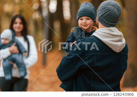 Boy is on the dad's hands. Father with his son on hands walking with mother that is with toddler Boy is on the dad's hands. Father with his son on hands walking with mother that is with toddler 126243906
