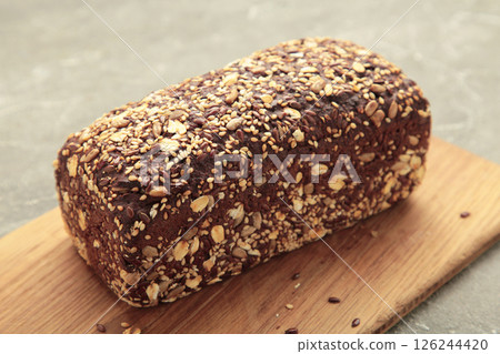 Wheat bread with mixed seeds on cutting board on grey background 126244420