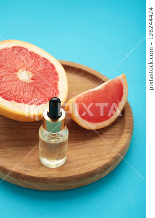 Bottle of essential oil and fresh grapefruits on blue background Bottle of essential oil and fresh grapefruits on blue background 126244424
