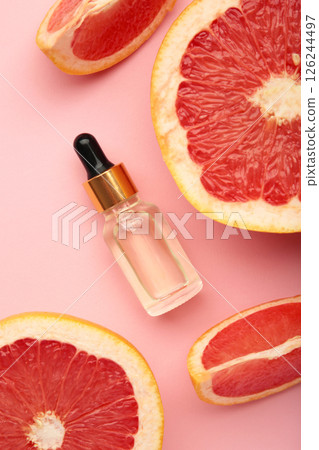 Bottle of essential oil and fresh grapefruits on pink background. Vertical photo Bottle of essential oil and fresh grapefruits on pink background. Vertical photo 126244497