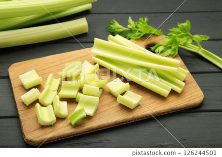 Fresh green cut celery on cutting board on black wooden background 126244501