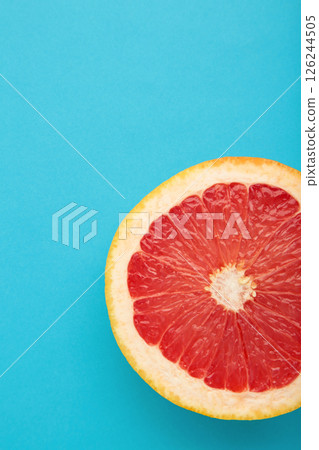 Half of fresh grapefruit on a blue background. Vertical photo 126244505