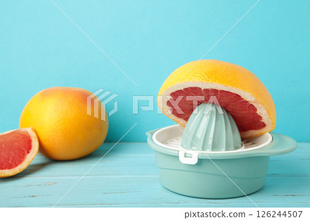 Juicer with freshly squeezed red grapefruit juice,with whole and sliced grapefruit on mint. 126244507