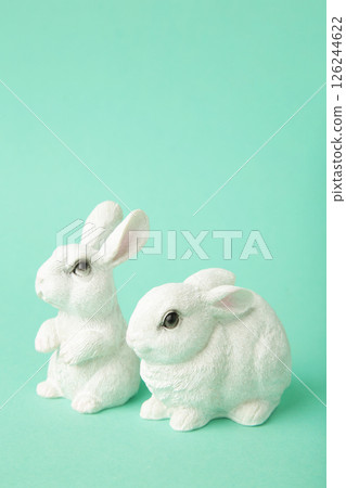 White ceramic rabbits on mint background. Vertical photo 126244622