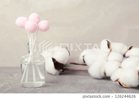 Air freshener on grey. White aroma diffuser bottle with sticks and cotton flower. Minimalism. Top view 126244626