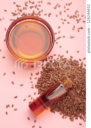 Flaxseeds with flaxseed oil in bowl on pink background. Vertical photo 126244652